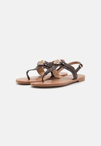 Bruine leren platte sandalen met kruisbanden, gouden ronde accenten en een gevoerd tan voetbed. Gestructureerd patroon op de banden. Verstelbare enkelgesp.