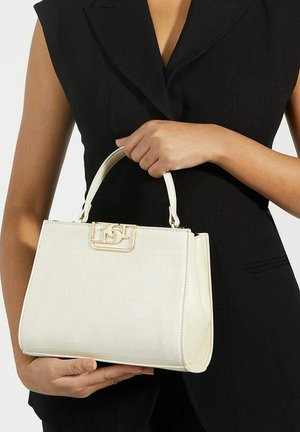 White faux leather handbag with a textured crocodile pattern, gold-tone hardware, and a structured design, held by a person wearing black.