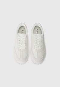 Valkoiset sneakerit, joissa on sileä nahka ja mokkapaneelit, litteät nauhat ja pyöreä kärki. Varustettu hienovaraisella brändäyksellä kielekkeessä.