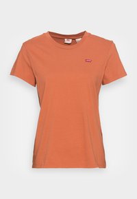 Camiseta de manga corta en algodón color naranja quemado, con un pequeño logo rojo de Levi's en el lado izquierdo del pecho. Cuello redondo clásico y ajuste casual.