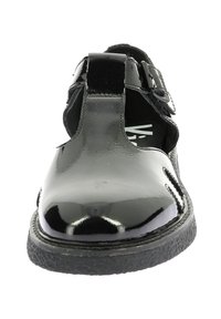 Chaussures en cuir verni noir avec une finition brillante, présentant un design découpé, une sangle à boucle réglable et une semelle en caoutchouc texturé.