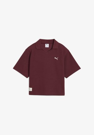 Polo shirt bordeaux, à manches courtes, avec un col en V, en tissu texturé, présentant un petit logo blanc sur la poitrine et une étiquette de marque sur l'ourlet.