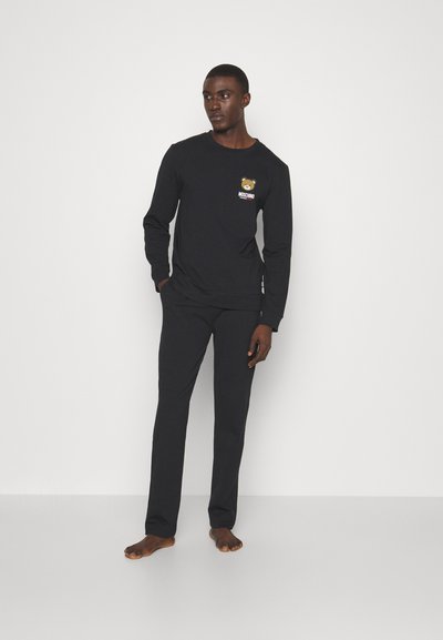 Black long-sleeve shirt and matching pants, made of soft fabric. Shirt features a bear graphic and "Moschino" text on the chest.