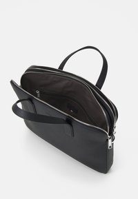 Czarna skórzana torba na laptopa o teksturowanym wykończeniu, z podwójnymi zamkami błyskawicznymi oraz górnym uchwytem do łatwego przenoszenia. Wnętrze wykończone ciemnym materiałem.