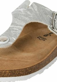 Silverskimrande sandal med en brunt mockafotbädd, vit gummisula och justerbar rem med en silvrig spänne och tryckknapp.