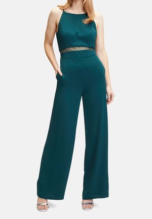 Zielony overall z dopasowaną górą z przezroczystą wstawką, szerokimi nogawkami i kieszeniami po bokach. Miękka tkanina o gładkiej teksturze.