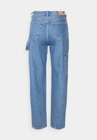 Jeans de mezclilla azul con un corte relajado, que cuentan con cinco bolsillos, trabillas para cinturón y un detalle de costura visible. Sin adornos ni patrones.
