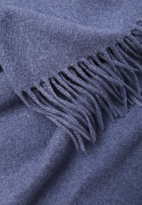 Villahuopa pehmeässä tummansinisessä värissä, jossa on sileä pinta. Reunoissa on pitkät, solmitut hapsut, jotka tuovat lisäyksityiskohtia.