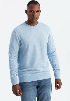 Sudadera de cuello redondo azul claro hecha de algodón texturizado, con puños y dobladillo acanalados, y un sutil logo en relieve en el pecho.