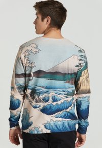 Pika-äärega dressipluus, millel on Jaapani inspireeritud maastiku trükk. Värvid: sinine, beež ja roheline, koos laine mustrite ja mägede detailidega.