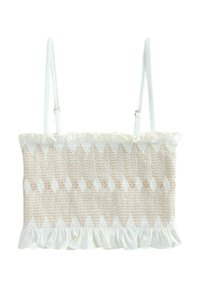 Vävd beige och vit topp med smockad textur och volangkant, med justerbara vita axelremmar. Designen inkluderar diamantmönster.