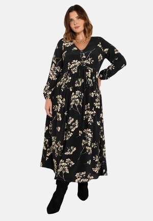 Schwarzes Maxikleid mit weißen Blumenmustern, mit langen Ärmeln, einem V-Ausschnitt und einem fließenden Rock. Mit Knöpfen am Oberteil akzentuiert.