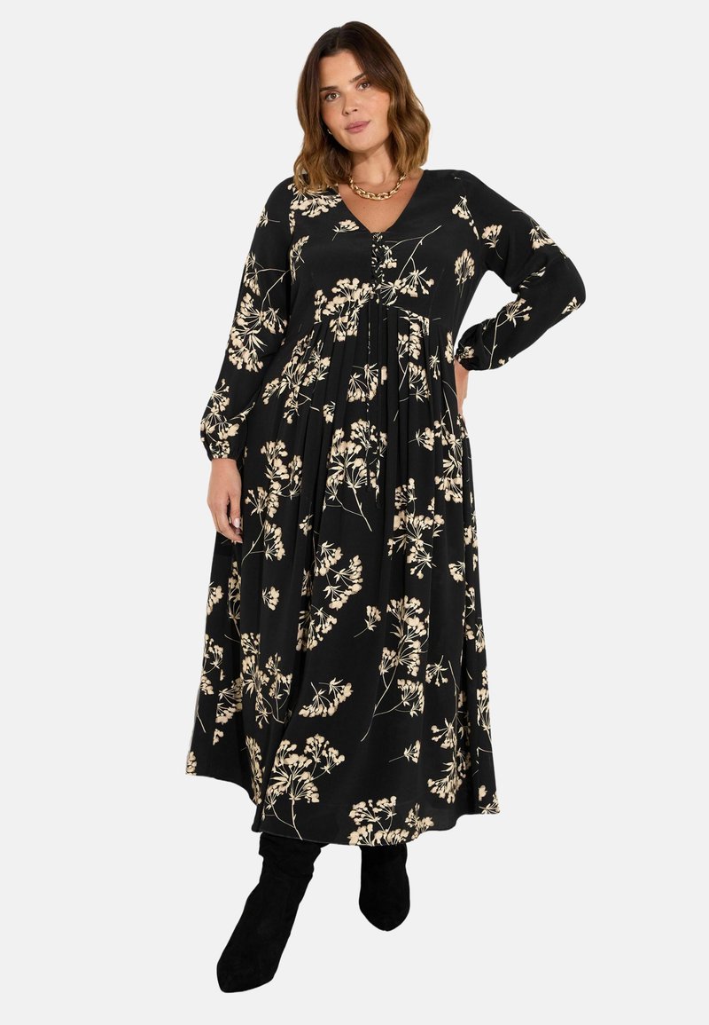Černé maxi šaty s bílým květinovým potiskem, dlouhými rukávy, výstřihem do V a splývavou sukní. Ozdobeny knoflíky na přední části.