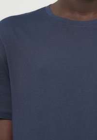 Μπλε ναυτικό βαμβακερό Τ-shirt με στρογγυλή λαιμόκοψη, κοντά μανίκια και απαλή, λεία υφή. Μινιμαλιστικός σχεδιασμός, χωρίς ορατά μοτίβα ή διακοσμητικά στοιχεία.