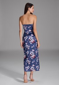 Vestido midi floral en azul marino con diseño sin tirantes, que presenta un corsé ajustado y una falda suelta. Destacado con flores blancas y rosas.