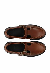 Chaussures en cuir marron à enfiler avec découpes et une sangle réglable. Présente des coutures blanches contrastantes et une semelle en caoutchouc noir.