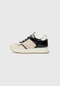 Sneakers featuring a blend of beige fabric with a subtle logo pattern, black patent leather accents, and white rubber sole with textured grip.
