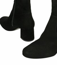 Zwarte suède enkellaarsjes met blokhakken en ritssluitingen aan de zijkant, voorkant en achterkant getoond op een witte achtergrond.