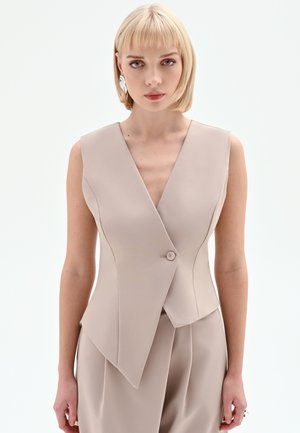 Gilet beige senza maniche con scollo a V profondo, taglio sartoriale, chiusura con un solo bottone e dettagli di cuciture sottili.