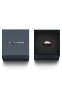 Daniel Wellingtonin rose gold -sormus tummansinisessä laatikossa, jossa on kultateksti. Laatikon sisäpuolella on musta samettitekstuuri; sormus on sileä pinta.