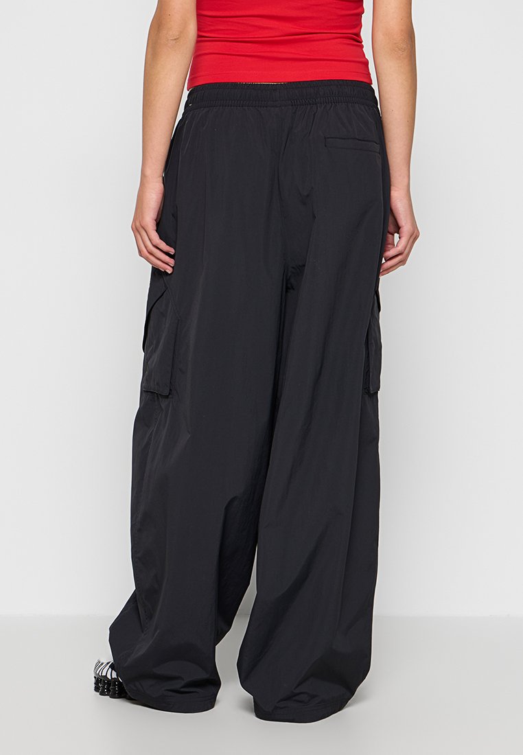 Pantaloni cargo neri con un design a gamba larga, vita elastica, tasche laterali e una texture in tessuto leggero.