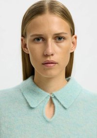 Hele sinine villasegune kampsun kraega, võtmeaugu kaelusega ja pehme tekstuuriga. Krae juures on nööp.