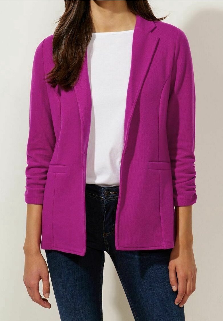 Přiléhavý fialový blejzr s dlouhými rukávy, otevřeným předním dílem a dvěma předními kapsami, kombinovaný s bílým topem a tmavými džíny. Hladká textura látky.
