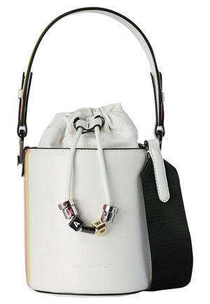 Mała biała torba typu bucket z zamknięciem na troczki, srebrno-czarne koraliki z literami na sznurku, czarny regulowany pasek na ramię.