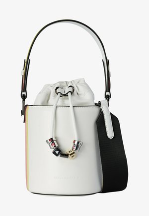 Mała biała torba typu bucket z zamknięciem na troczki, srebrno-czarne koraliki z literami na sznurku, czarny regulowany pasek na ramię.