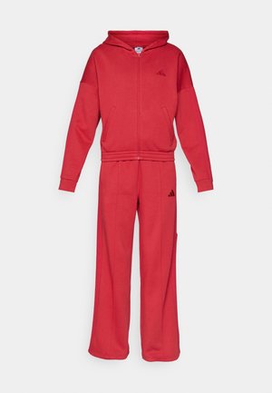 Red hoodie and jogger set made from soft fabric. Features a zip front, hood, and elastic cuffs. Logo on chest and pants. Relaxed fit.