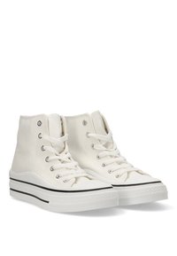 Zapatillas altas blancas de lona, con un diseño clásico que incluye ojales plateados, cordones blancos y suelas de goma negras con una franja.