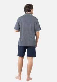 Chemise à motifs bleu marine à manches courtes avec un col, associée à un short bleu marine. Fabriquée en tissu léger, avec peu de détails visibles.