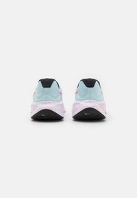 Des chaussures de sport bleu clair avec une surface texturée, des éclats roses sur la semelle blanche et un contre-pointe noir affichant un logo.