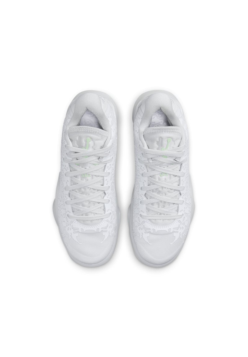 Une paire de baskets blanches avec des motifs texturés complexes et un logo vert clair sur la languette, vue de dessus sur un fond blanc.
