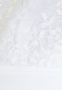 Tecidos de renda brancos com padrões florais intricados, sobrepostos a um material base branco suave. A textura é delicada e transparente.