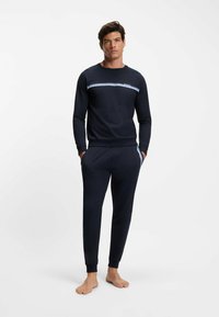 Completo lounge blu navy composto da felpa girocollo con una striscia orizzontale azzurro chiaro e pantaloni affusolati abbinati con polsini a costine.