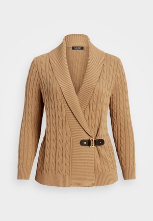 Cable knit cardigan in a light beige color. Features a large shawl collar, belted waist with a brown strap and gold buckle detail.