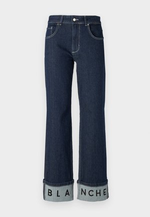 Jeanși din denim albastru închis cu picior larg, având un tiv pliat pe care este scris "BLANCHE" cu litere negre îndrăznețe pe un tiv de un albastru deschis.