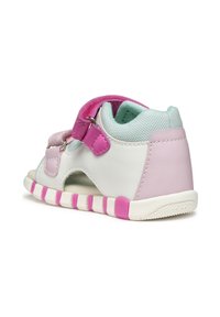 Białe i jasnoniebieskie sneakersy z różowymi akcentami, wyposażone w pasek na rzepy oraz wycięcia, o strukturalnej powierzchni i gumowej podeszwie.