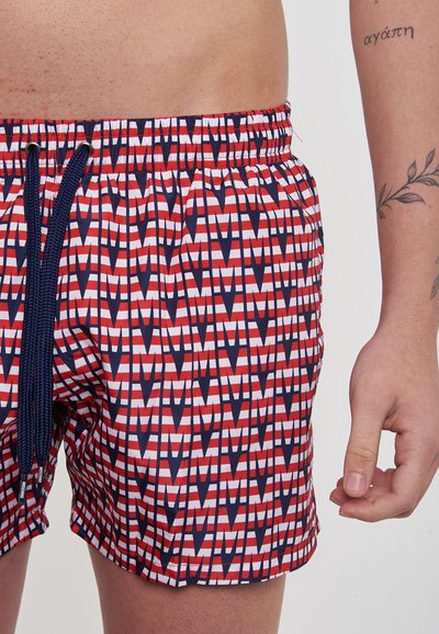 Costume da mare rosso, bianco e blu navy con motivo geometrico. Presenta una vita elasticizzata e un cordoncino blu per la regolazione.