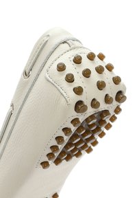 Zapato de cuero blanco con acabado texturizado, que presenta clavos de goma marrón en la suela y a lo largo del borde superior para mayor agarre y diseño.