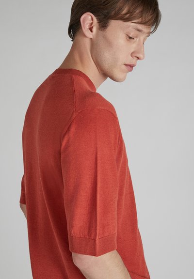 Sweter z krótkim rękawem o luźnym kroju w stonowanym czerwonym odcieniu. Wykonany z miękkiego, teksturowanego materiału, z prążkowanymi mankietami i okrągłym dekoltem.