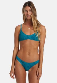 Tealfärgad ribbad bikinitopp med korta ärmar och låg midja, båda med subtilt mönster och textur.