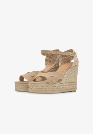 Sandales compensées beiges avec talons plateforme tissés, brides croisées sur les orteils et brides de cheville ajustables avec boucles.