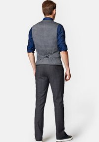 Szary i niebieski kamizelka w kratę na niebieskiej koszuli, w połączeniu z szarymi spodniami w kratkę. Kamizelka ma tylną regulację.