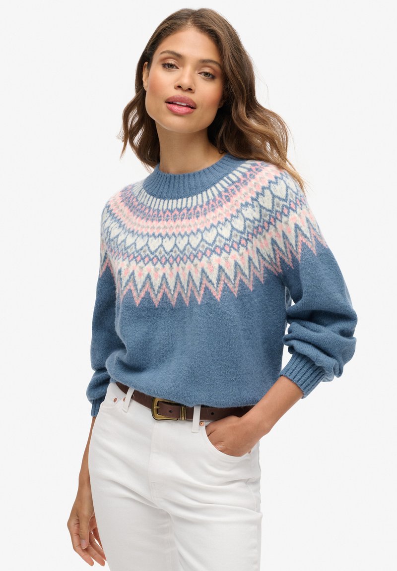 Blauer Strickpullover mit rundem Ausschnitt, der ein buntes Fair Isle-Muster in Rosa und Weiß an der Passe aufweist. Lockere Passform und gerippte Bündchen.