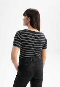 Zwart-wit gestreepte top met korte mouwen en een ronde hals, gecombineerd met hoge zwarte denim jeans met achterzakken.