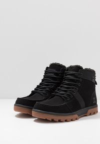 Czarne zamszowe botki z siateczkową wstawką, gumową podeszwą i futrzanym ociepleniem. Posiadają okrągłe sznurowadła oraz logo z boku. Wysoki krój.