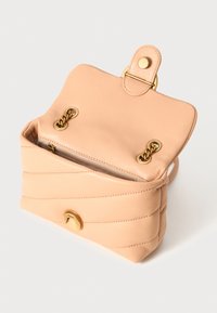 Bolsa de mão em couro pêssego com textura matelassada, detalhes em dourado e um bolso interior com fecho éclair. Apresenta uma aba com fecho de pressão e detalhes em corrente.