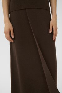 Brown wool skirt with a sleek, A-line shape. Features a draped front and smooth texture. Paired with a matching knit top.